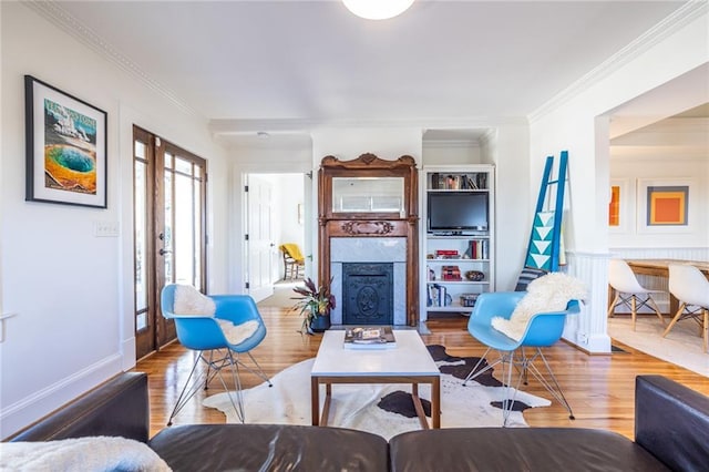 living room featuring french doors, crown molding, a fireplace with flush hearth, wood finished floors, and baseboards