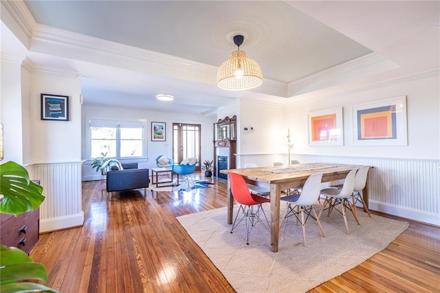 dining room featuring a tray ceiling, hardwood / wood-style floors, and wainscoting