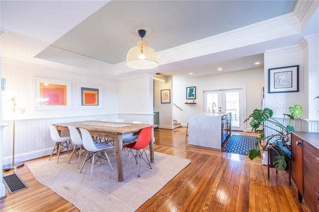 dining space featuring wainscoting, light wood-type flooring, and crown molding