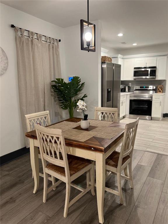 dining space featuring baseboards, recessed lighting, and wood tiled floor