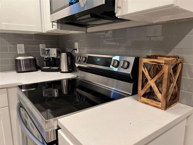 kitchen featuring stainless steel appliances, white cabinets, and decorative backsplash