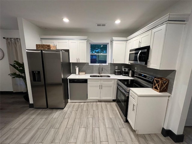 kitchen featuring stainless steel appliances, light countertops, white cabinets, and a sink