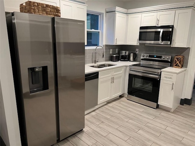 kitchen featuring stainless steel appliances, a sink, white cabinets, light countertops, and decorative backsplash