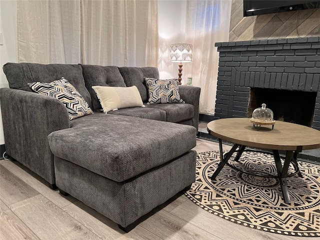 living room with a brick fireplace and wood finished floors