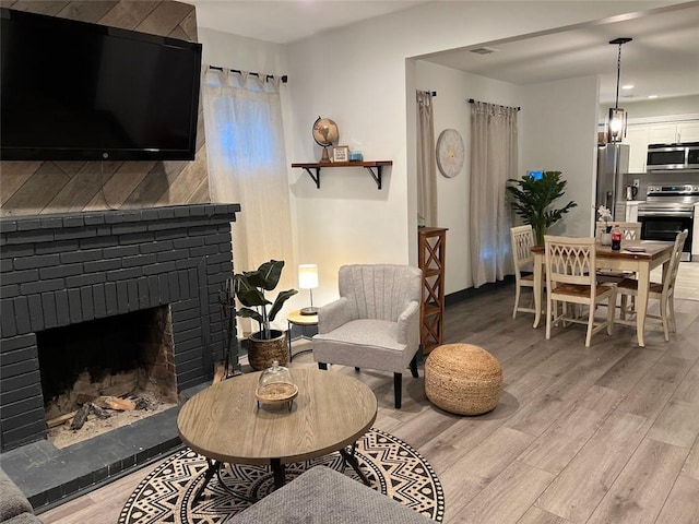 living area with a brick fireplace and light wood-style flooring