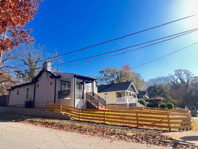 bungalow-style home with a fenced front yard, a chimney, and stairs