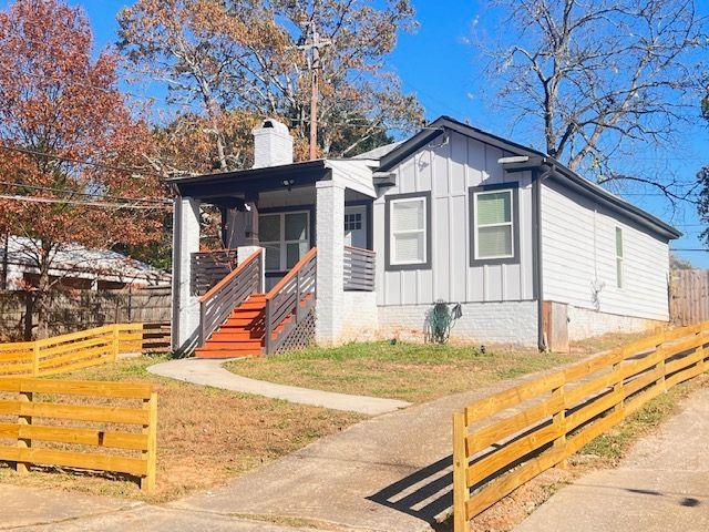 bungalow-style house featuring board and batten siding, a chimney, and fence