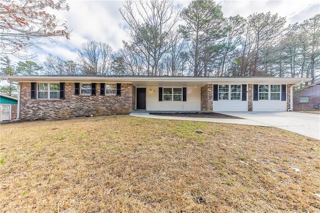 ranch-style house with concrete driveway, brick siding, and a front yard