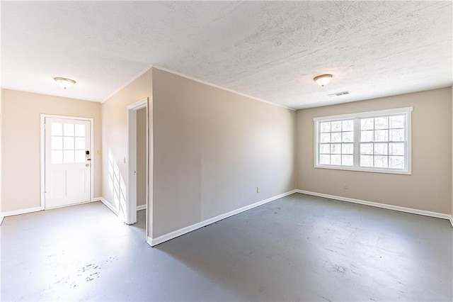 empty room with concrete flooring, a textured ceiling, visible vents, and baseboards