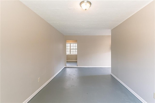 spare room featuring finished concrete floors and baseboards