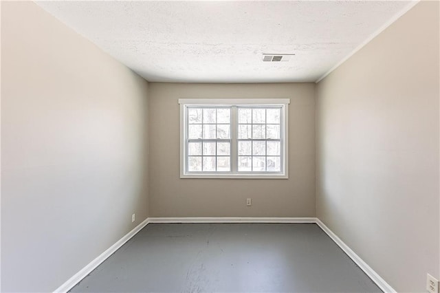 empty room featuring visible vents, concrete floors, a textured ceiling, and baseboards