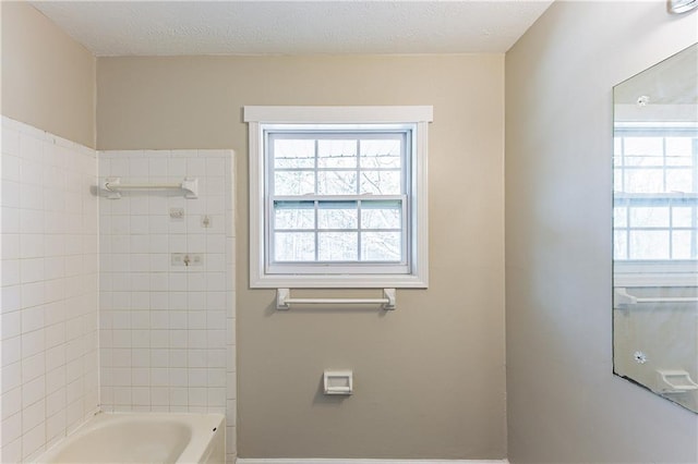 bathroom with a healthy amount of sunlight, shower / tub combination, and a textured ceiling