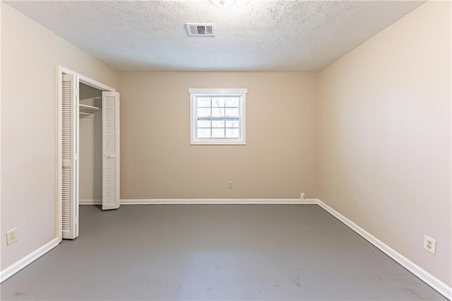 unfurnished bedroom with a closet, visible vents, concrete floors, and baseboards