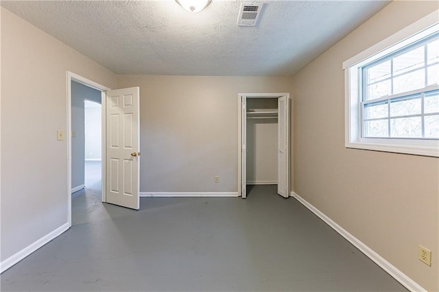 unfurnished bedroom featuring baseboards, concrete floors, visible vents, and a closet