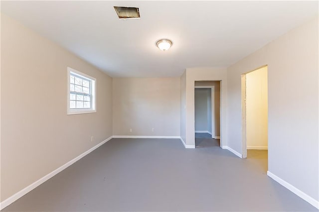 unfurnished room featuring concrete floors and baseboards