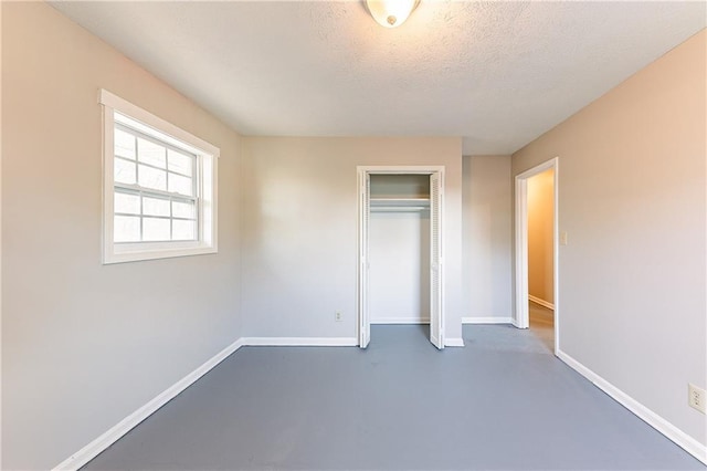 unfurnished bedroom featuring a textured ceiling, concrete floors, a closet, and baseboards