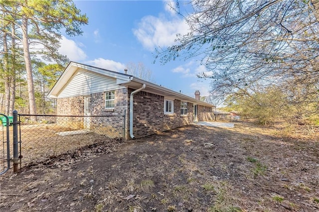 view of side of property featuring a chimney, fence, and brick siding