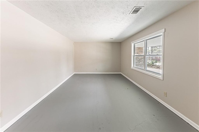 spare room with visible vents, concrete floors, a textured ceiling, and baseboards