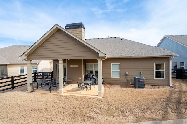 back of house with roof with shingles, a patio, a chimney, fence, and cooling unit