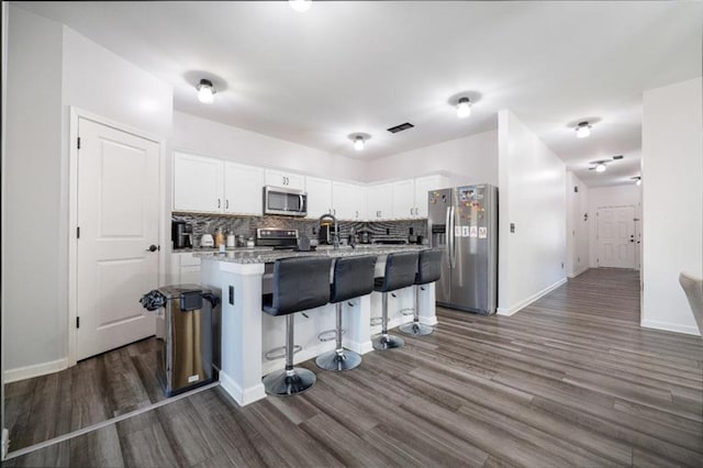 155 Knightsbridge Ln, Winder, GA 30680 - kitchen featuring appliances with stainless steel finishes, dark wood-type flooring, white cabinets, and tasteful backsplash