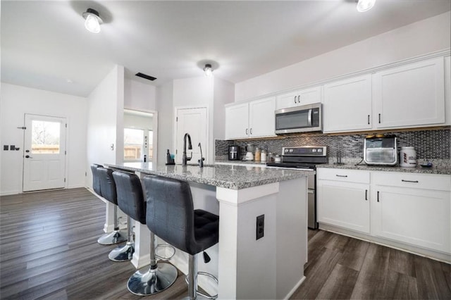 155 Knightsbridge Ln, Winder, GA 30680 - kitchen featuring stainless steel appliances, dark wood finished floors, tasteful backsplash, light stone counters, and white cabinetry