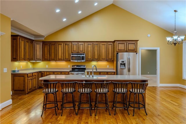 kitchen featuring a kitchen bar, appliances with stainless steel finishes, sink, a chandelier, and an island with sink