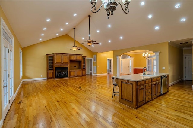 kitchen featuring a large island, sink, stainless steel dishwasher, decorative columns, and ceiling fan with notable chandelier