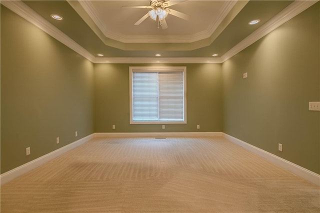 carpeted empty room featuring ceiling fan, a raised ceiling, and crown molding