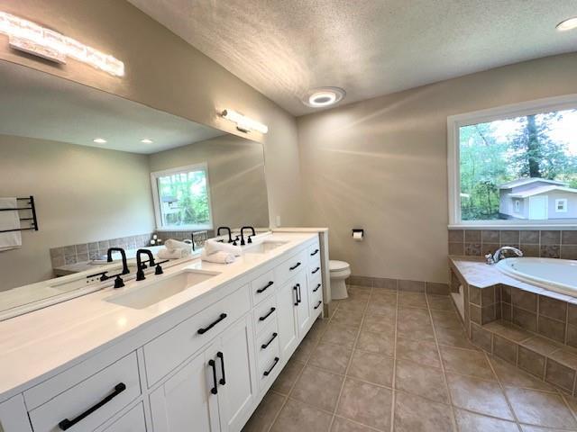 942 Batesville Rd, Canton, GA 30115 - full bathroom featuring tile patterned flooring, double vanity, toilet, baseboards, and a relaxing tiled tub