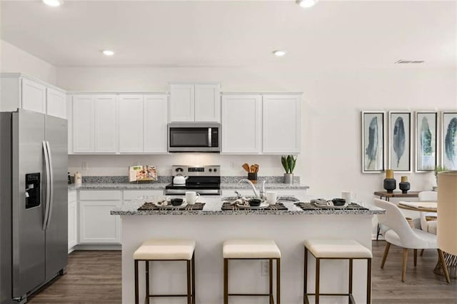 1315 Aura Ln, Lawrenceville, GA 30045 - kitchen with stainless steel appliances, a kitchen breakfast bar, white cabinets, light stone countertops, and recessed lighting