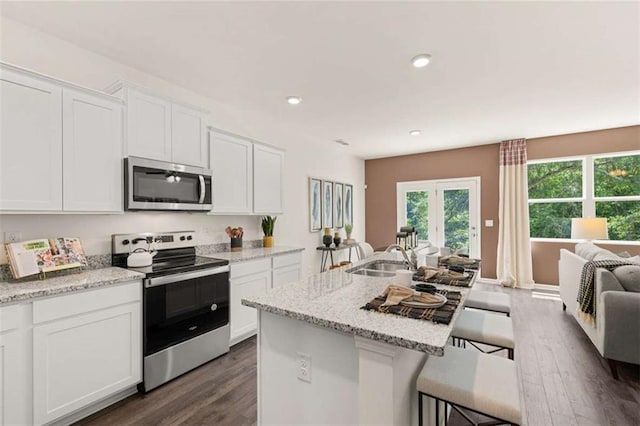 1315 Aura Ln, Lawrenceville, GA 30045 - kitchen featuring appliances with stainless steel finishes, open floor plan, dark wood-style flooring, a kitchen breakfast bar, and recessed lighting
