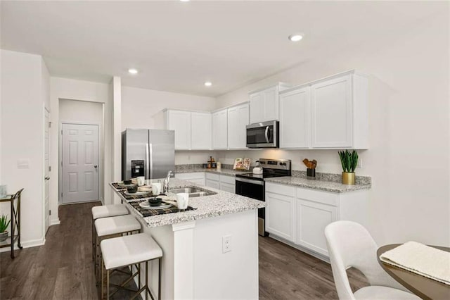 1315 Aura Ln, Lawrenceville, GA 30045 - kitchen featuring stainless steel appliances, white cabinetry, a breakfast bar area, an island with sink, and recessed lighting