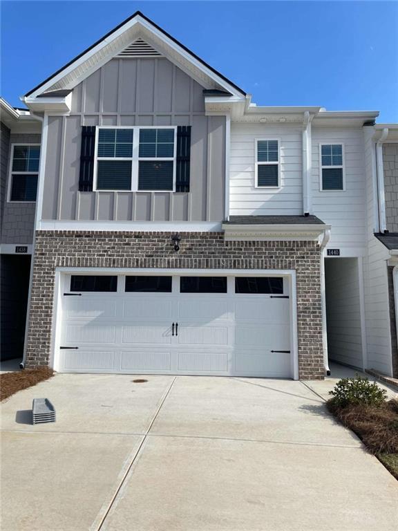 1315 Aura Ln, Lawrenceville, GA 30045 - view of property featuring an attached garage, brick siding, driveway, and board and batten siding