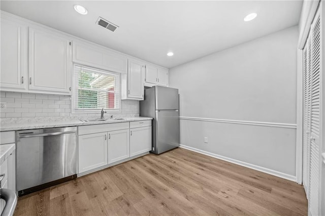 kitchen with tasteful backsplash, white cabinetry, appliances with stainless steel finishes, and light wood-type flooring