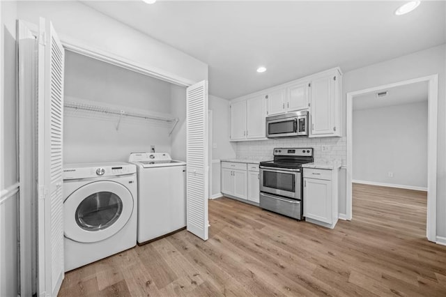 laundry room with independent washer and dryer and light hardwood / wood-style flooring