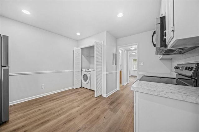 kitchen featuring appliances with stainless steel finishes, tasteful backsplash, washer / dryer, white cabinets, and light hardwood / wood-style floors