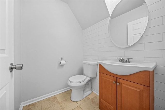 bathroom featuring vanity, tile patterned floors, lofted ceiling, and toilet