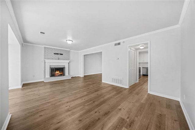 unfurnished living room featuring crown molding, a brick fireplace, and hardwood / wood-style flooring