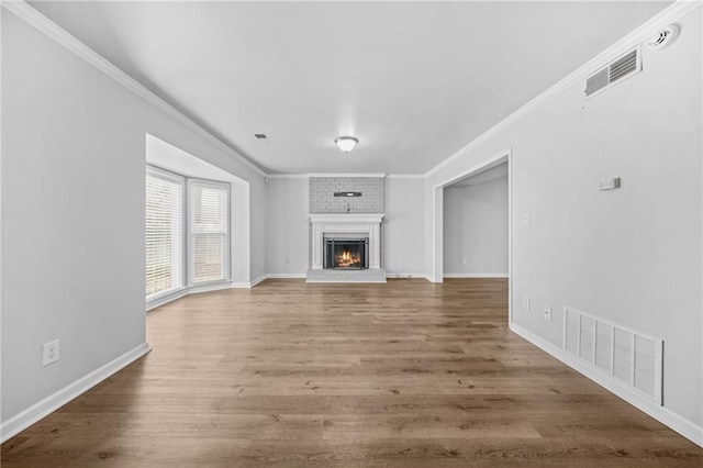 unfurnished living room with crown molding, a brick fireplace, and wood-type flooring