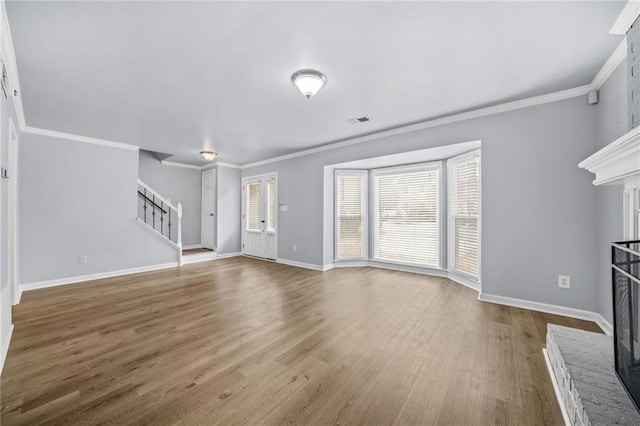 unfurnished living room featuring a brick fireplace, hardwood / wood-style flooring, and ornamental molding