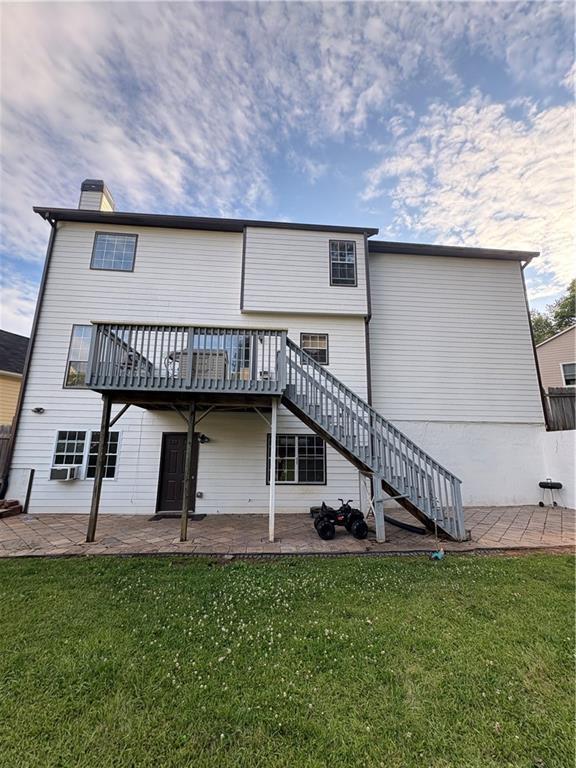 rear view of property featuring a patio area, stairs, a yard, and a deck