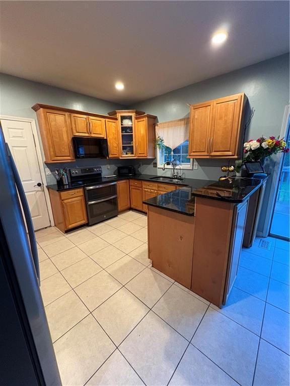 kitchen featuring range with two ovens, black microwave, a peninsula, brown cabinetry, and recessed lighting