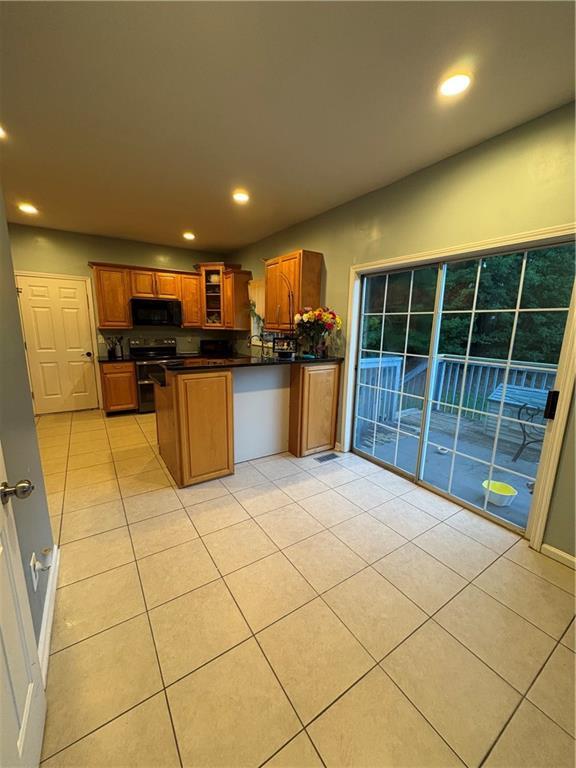 1951 Bergerac Ct SW, Marietta, GA 30008 - kitchen with black appliances, dark countertops, a peninsula, brown cabinets, and light tile patterned floors