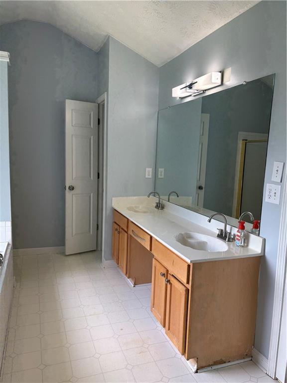 bathroom featuring lofted ceiling and double vanity