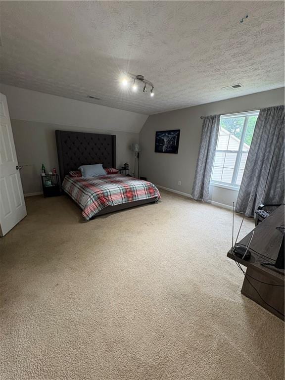 bedroom with light carpet, baseboards, and a textured ceiling