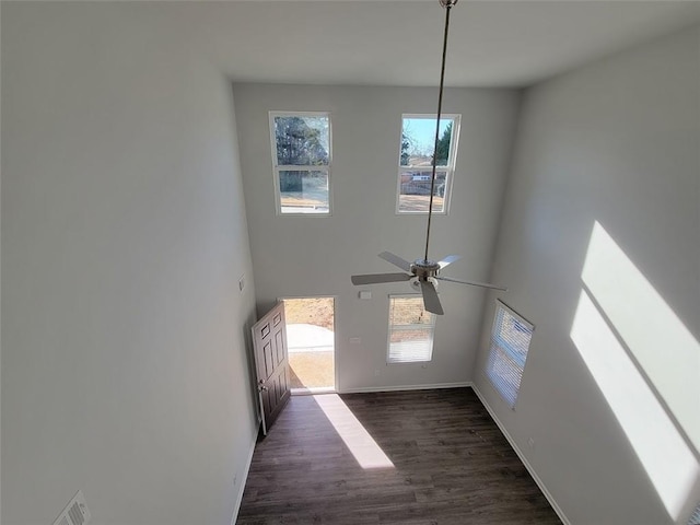 interior space featuring dark wood-type flooring, ceiling fan, and a high ceiling