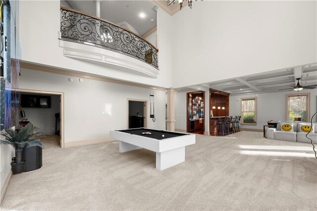 rec room with light carpet, a dry bar, baseboards, a towering ceiling, and ornate columns