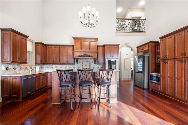 kitchen featuring a center island, a high ceiling, stainless steel appliances, and decorative light fixtures