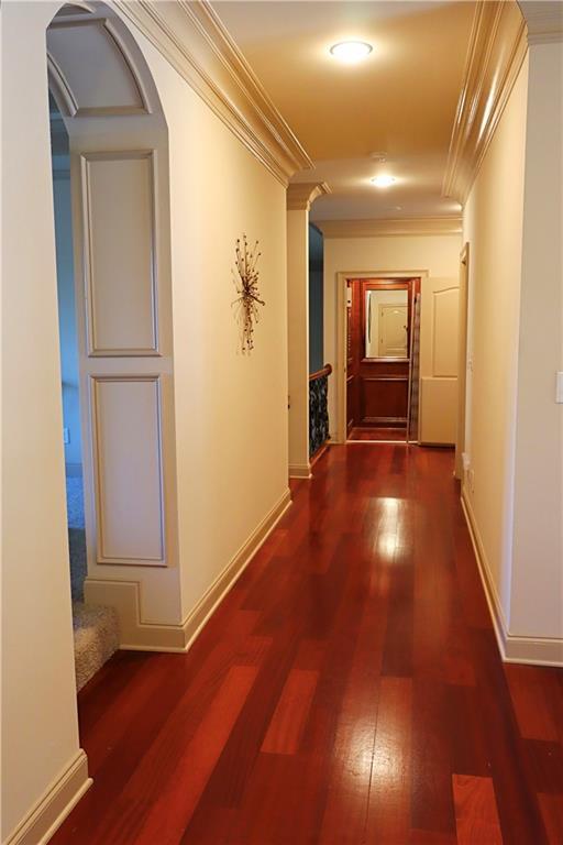 hallway with dark wood-style floors, baseboards, and crown molding