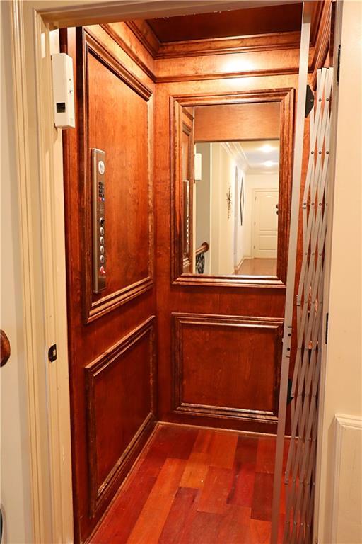 room details with elevator, crown molding, and wood finished floors